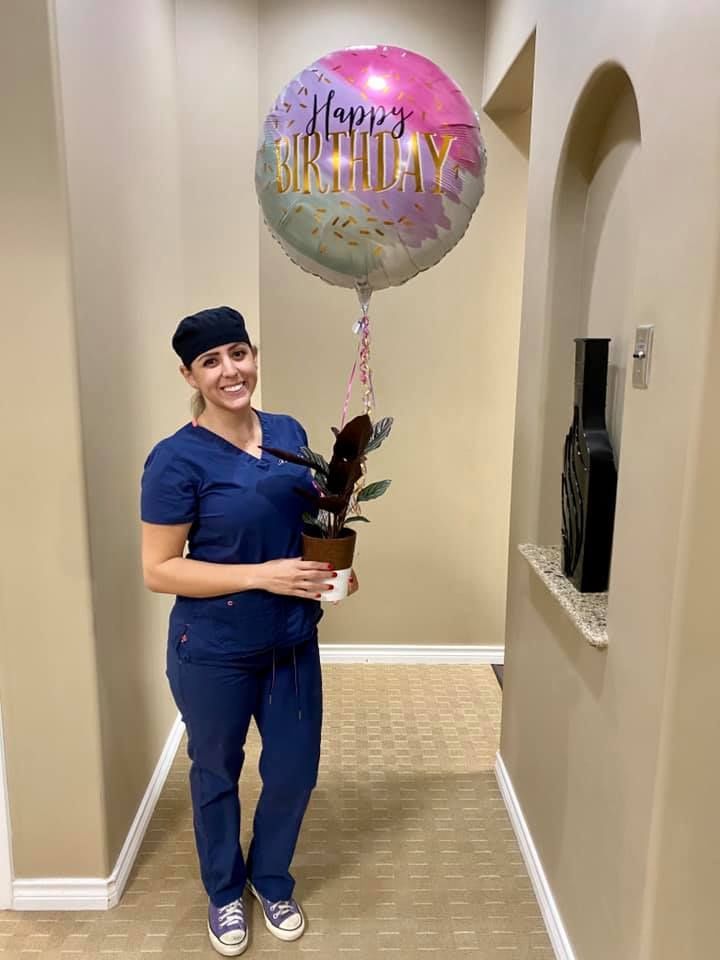 Woman in blue scrubs holds a plant and a 