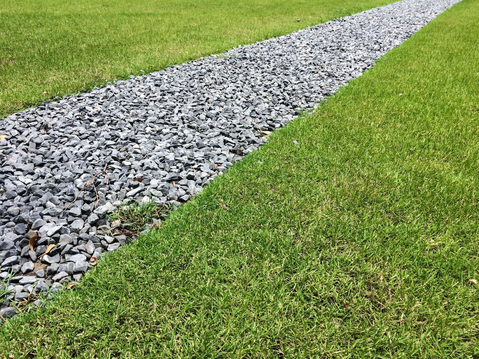 Gravel path cutting through a green grassy field