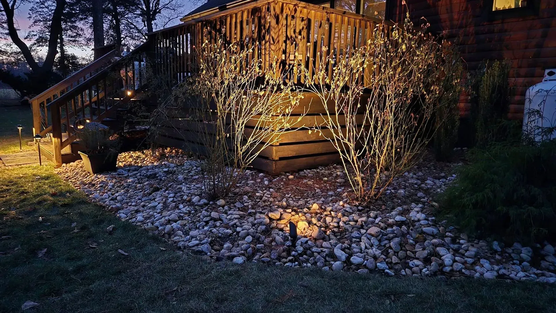 Wooden cabin at dusk with icicle lights, snow-covered ground, and a glowing outdoor lantern.