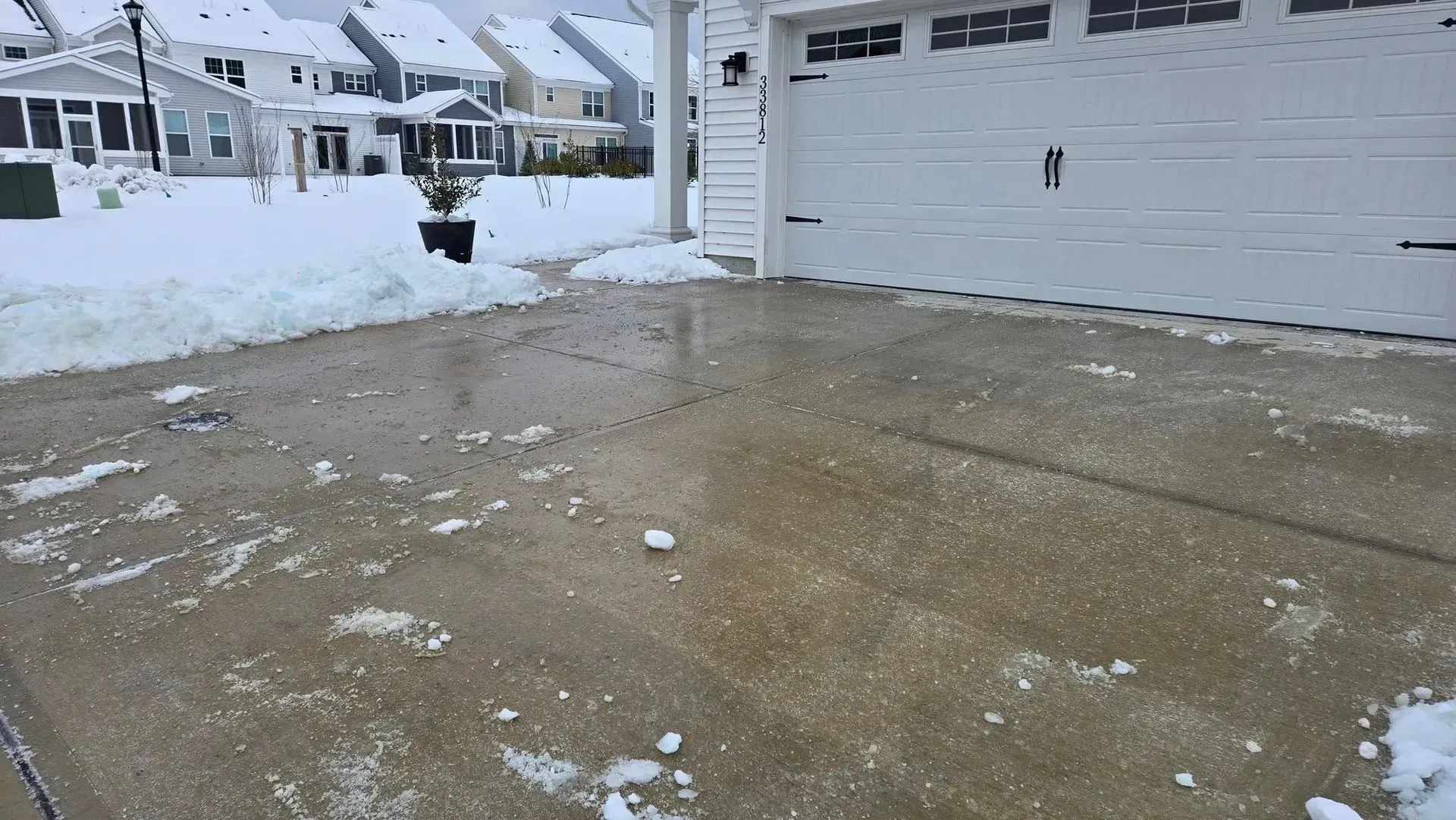 Snow-covered driveway and garage in a suburban neighborhood