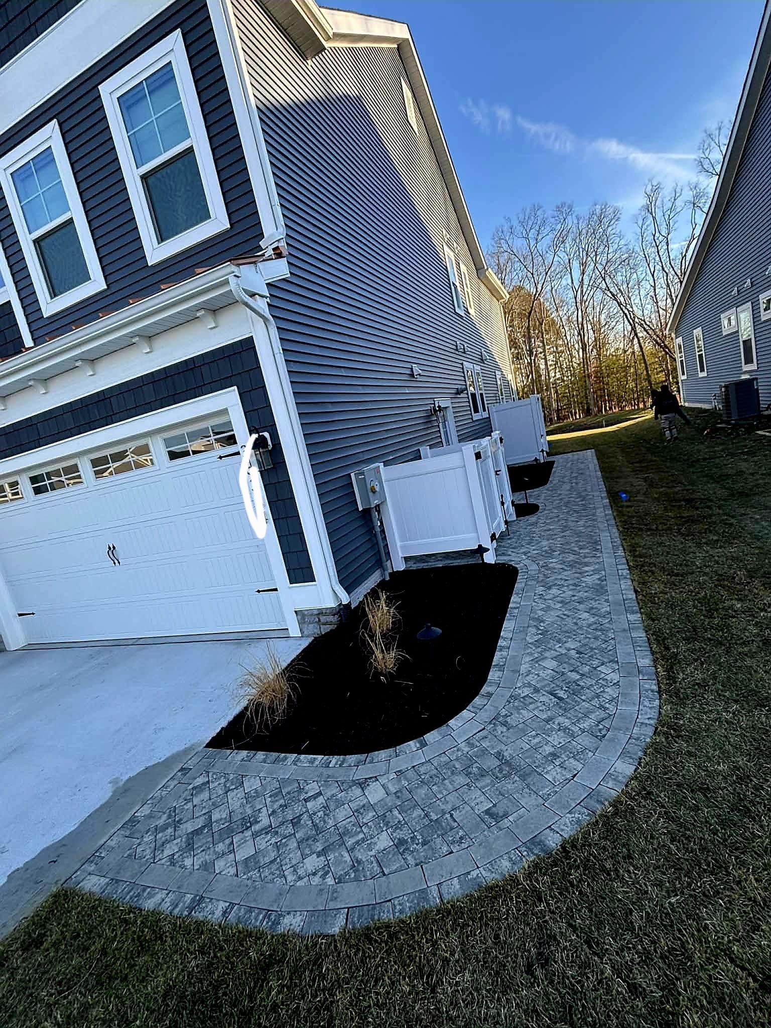 Suburban house exterior with white garage, curved gravel bed, and black-and-white striped siding panels