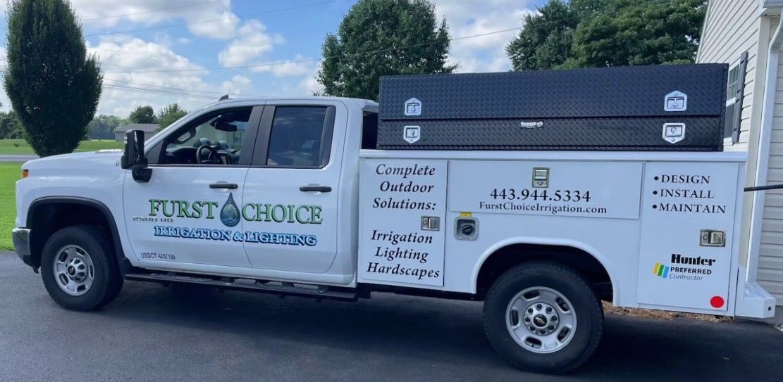 White utility truck with company logos parked outdoors on a sunny day