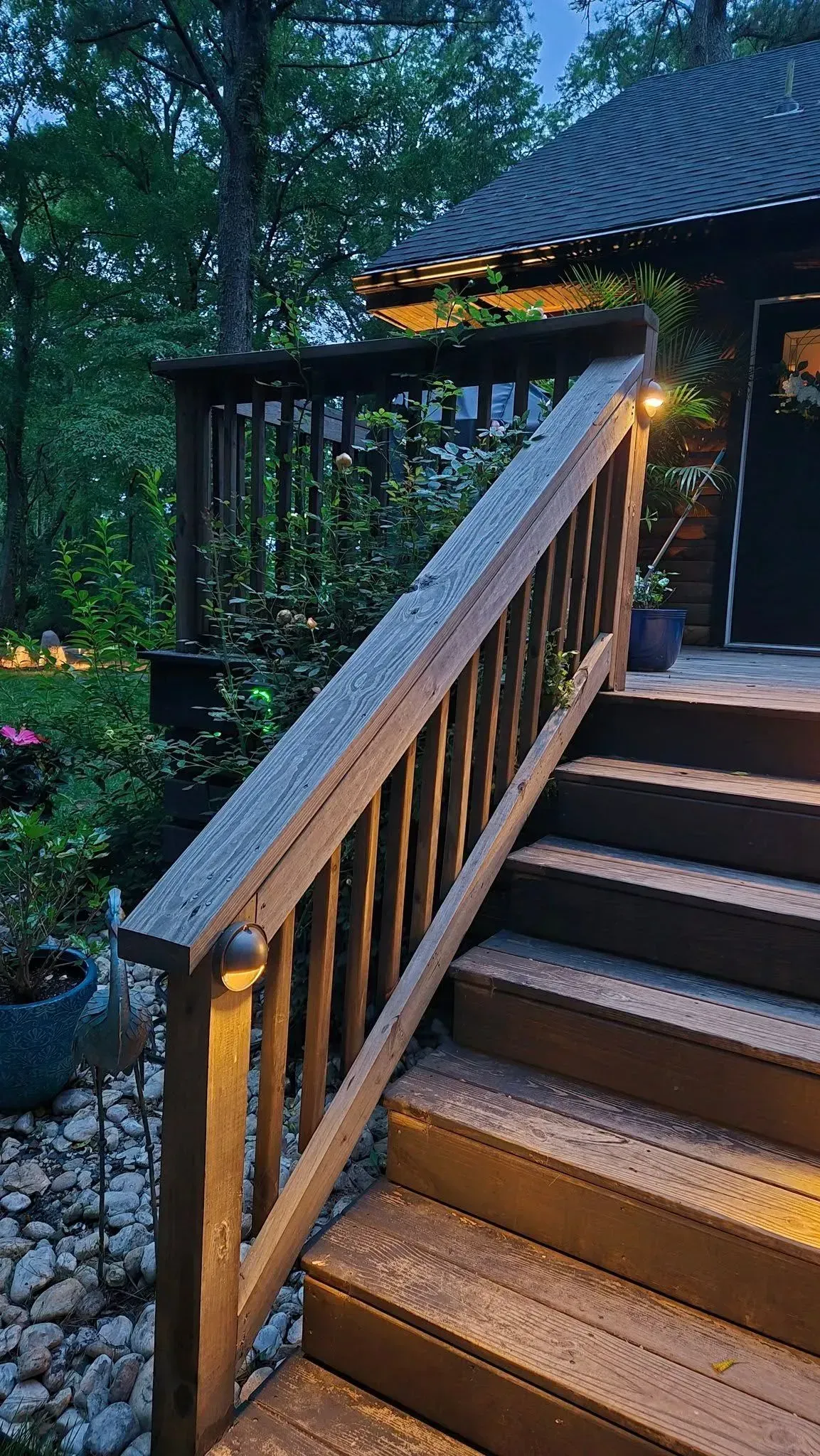 Wooden ramp and steps leading to a lit cabin entrance at dusk