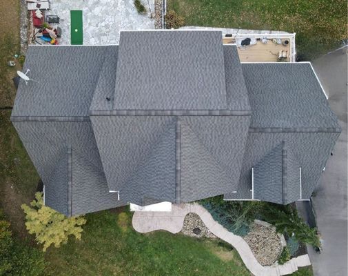 Overhead view of a house with a gray shingled roof, set on a green lawn with a winding stone path.
