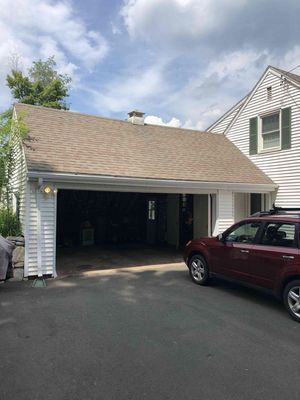 Garage attached to a house with an open garage door; a red car sits nearby.