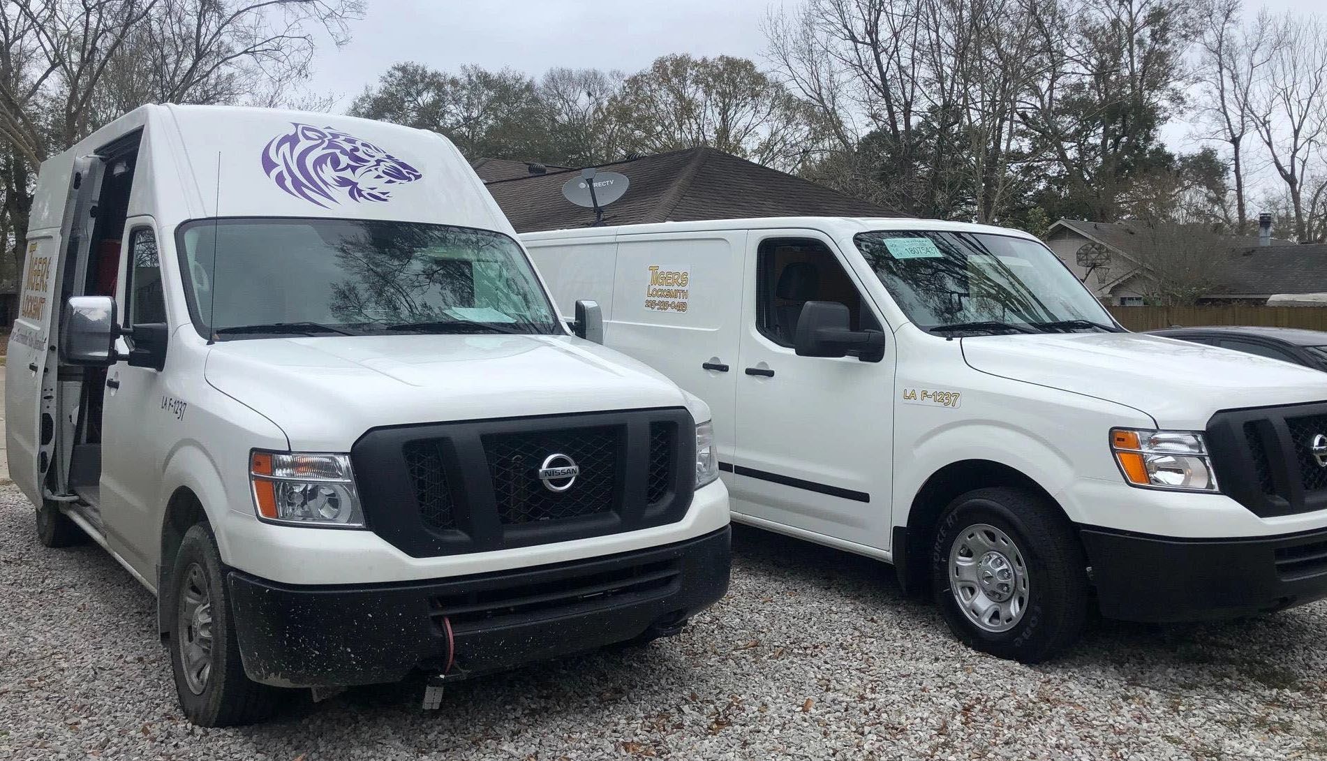 Two Tigers Locksmith service vans are parked next to each other in a gravel lot