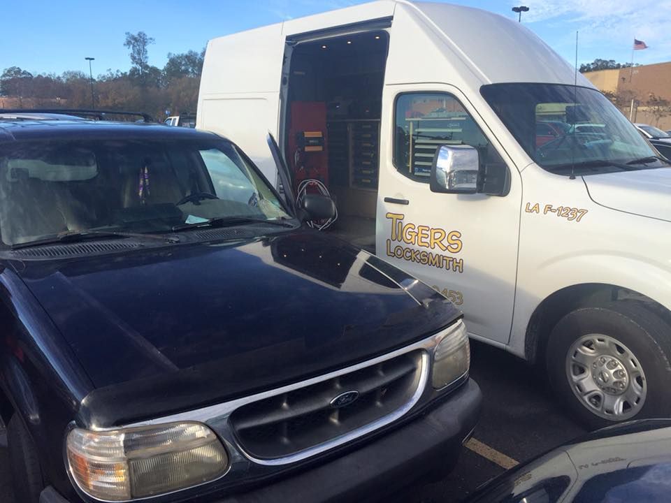 A black car is parked next to an open service van