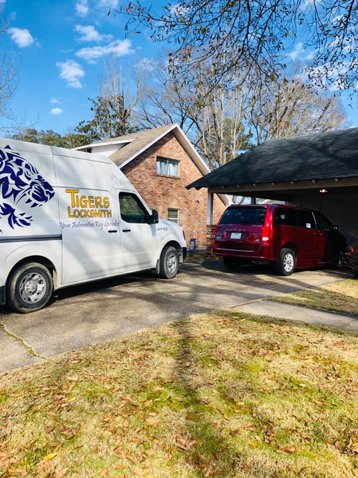 A white van and a red vehicle are parked in front of a house
