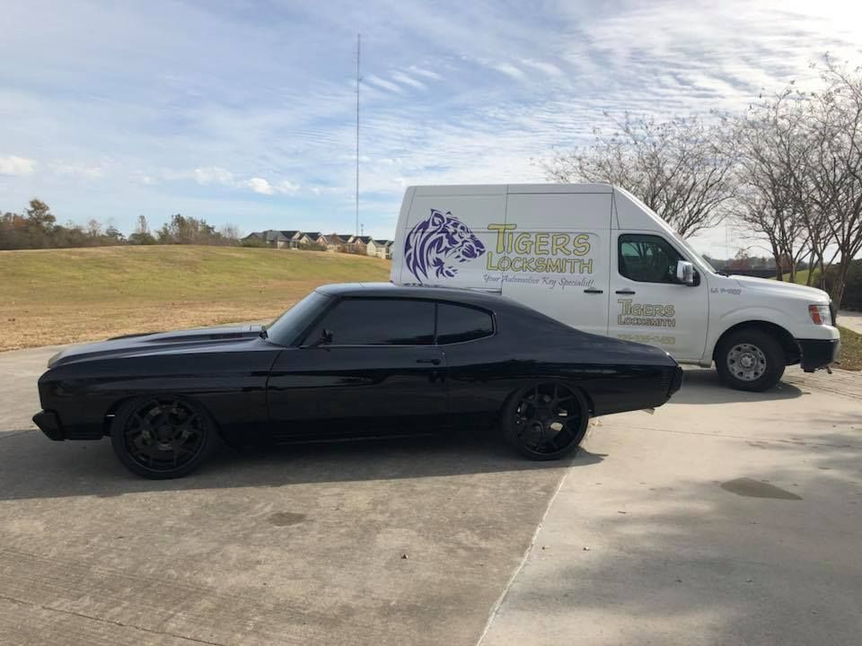 A black car is parked next to Tigers Locksmith's service van