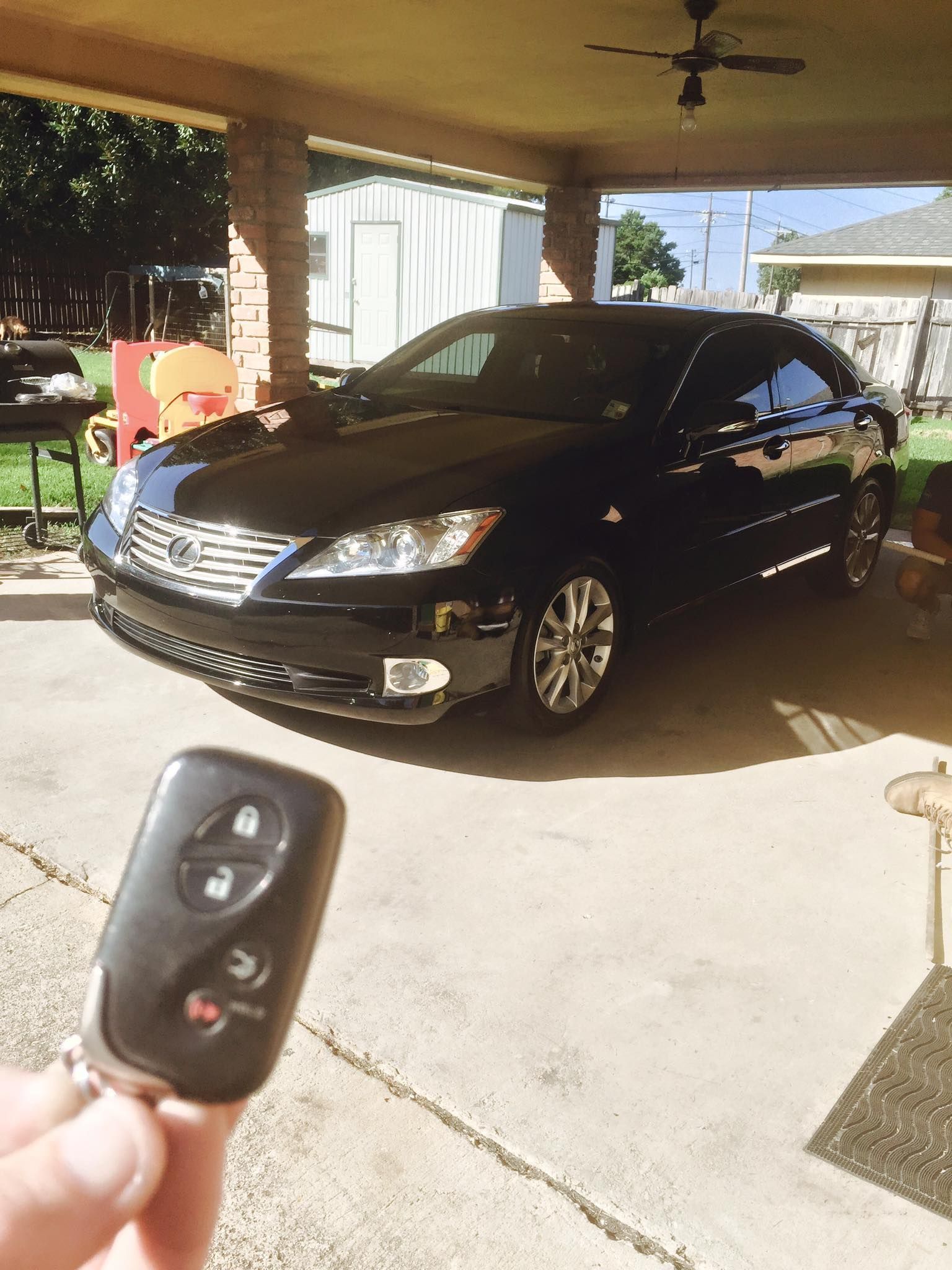 A person is holding a remote control in front of a black car