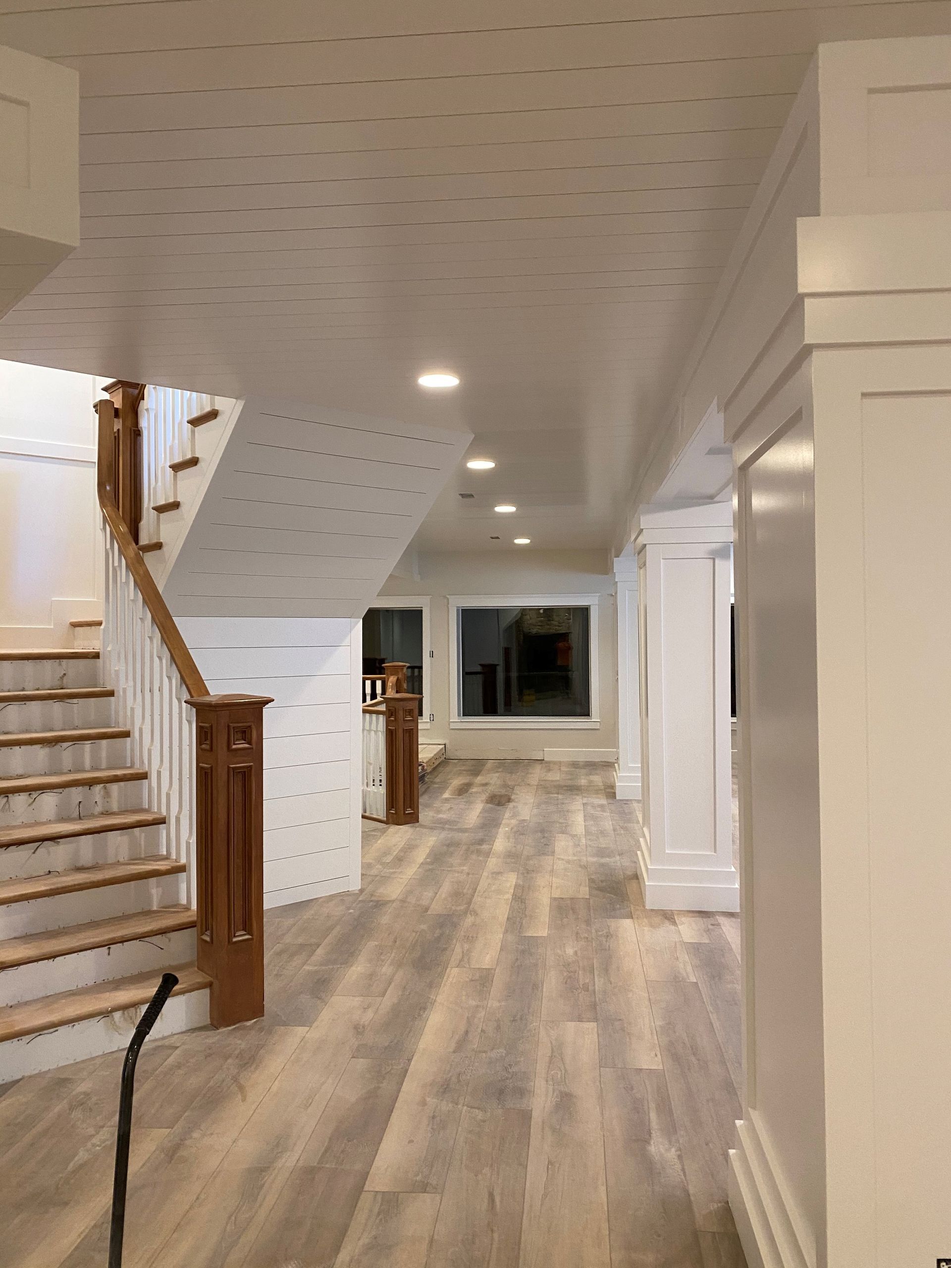 A hallway with wooden floors and stairs in a house