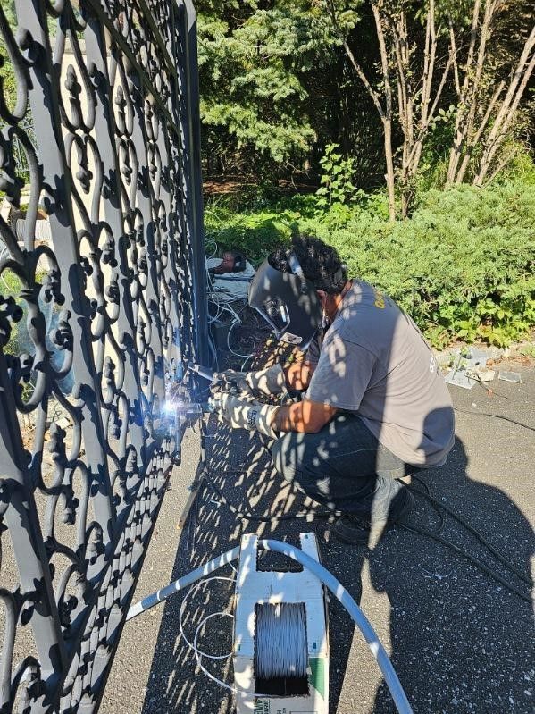 A man is welding a gate on the side of the road