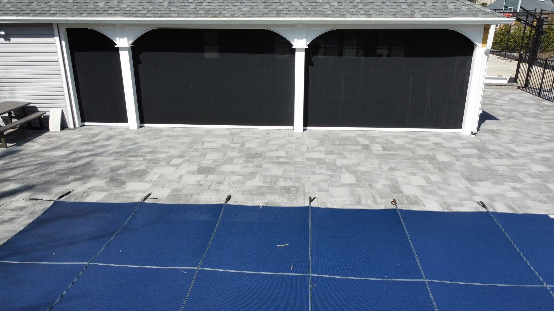 A blue pool cover is sitting on the ground in front of a garage