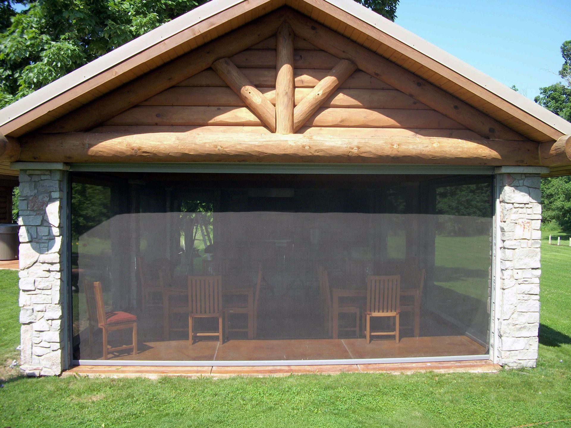 A screened in porch with chairs and a wooden roof