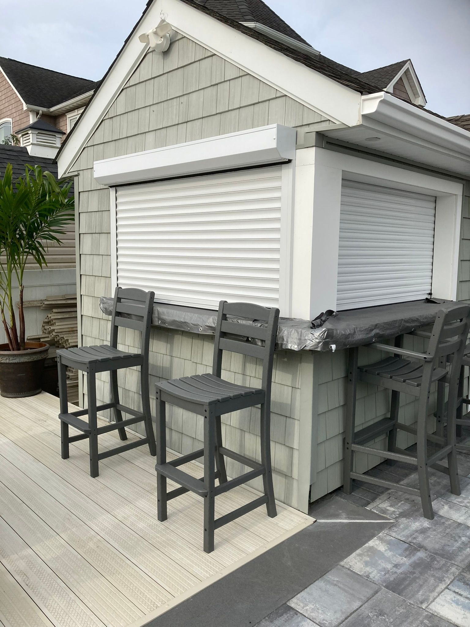 Outdoor bar with gray bar stools and rolling shutter.