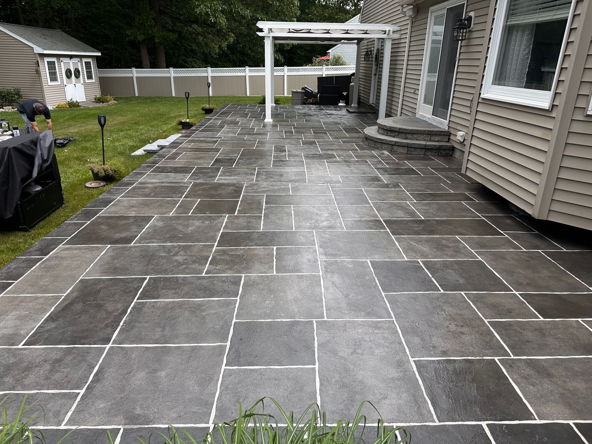 A patio with a shed in the background and a house in the background