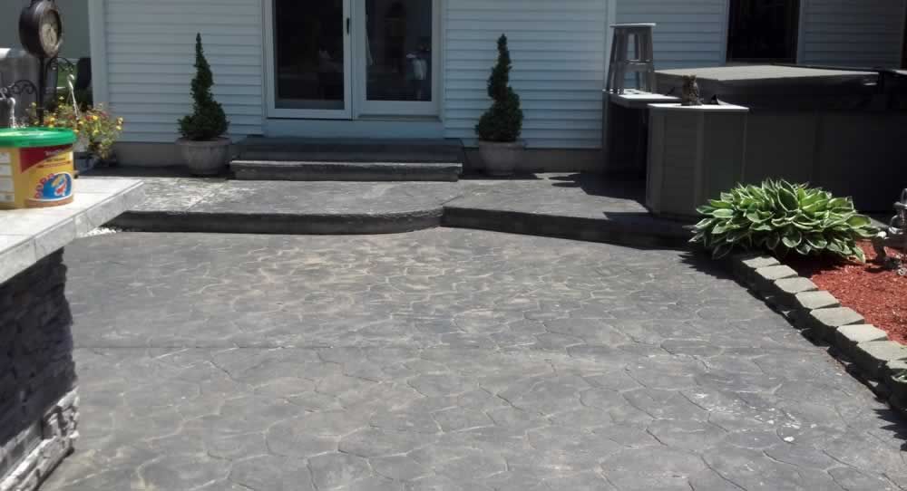 A concrete patio with a white house in the background