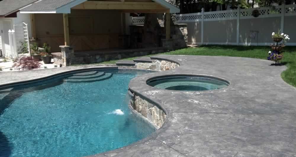 A large swimming pool with a hot tub next to it