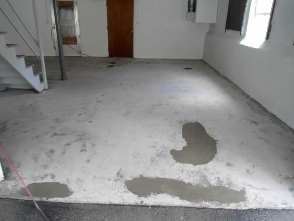 A concrete floor in a room with stairs and a door.