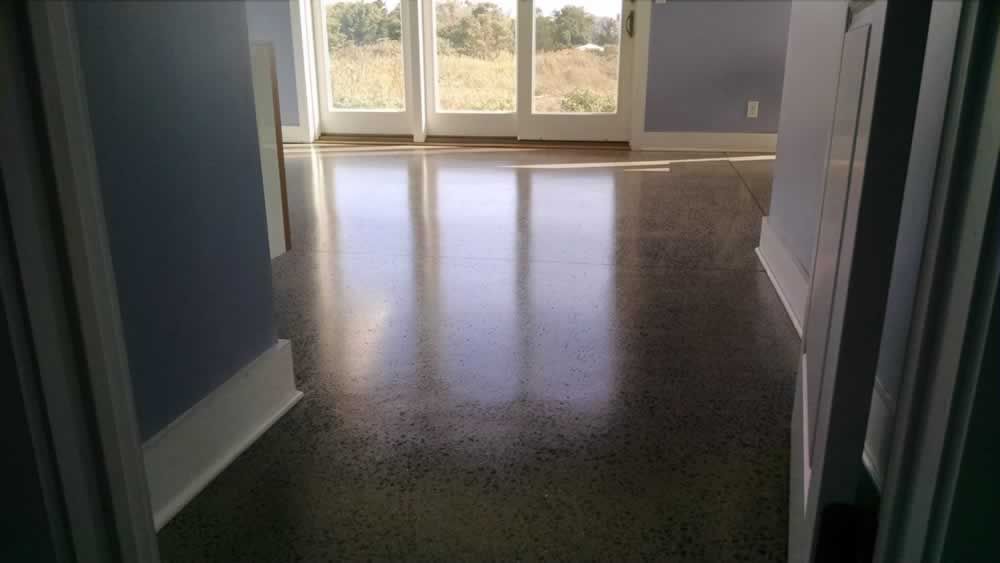 A hallway with a shiny concrete floor and sliding glass doors.
