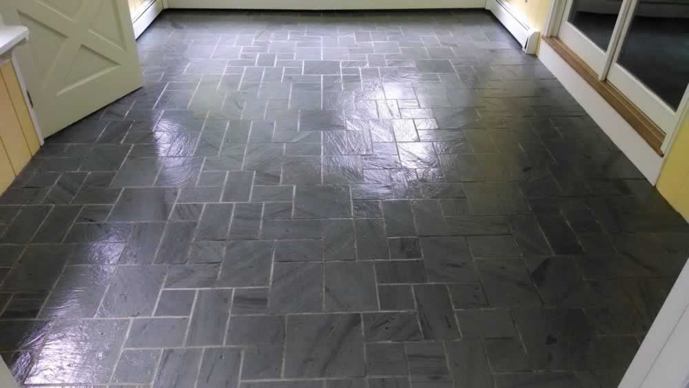 A kitchen with a black tile floor and white cabinets