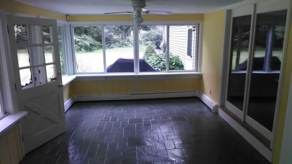 An empty room with a lot of windows and a ceiling fan