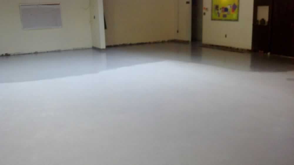 A large room with a white floor and a painting on the wall.