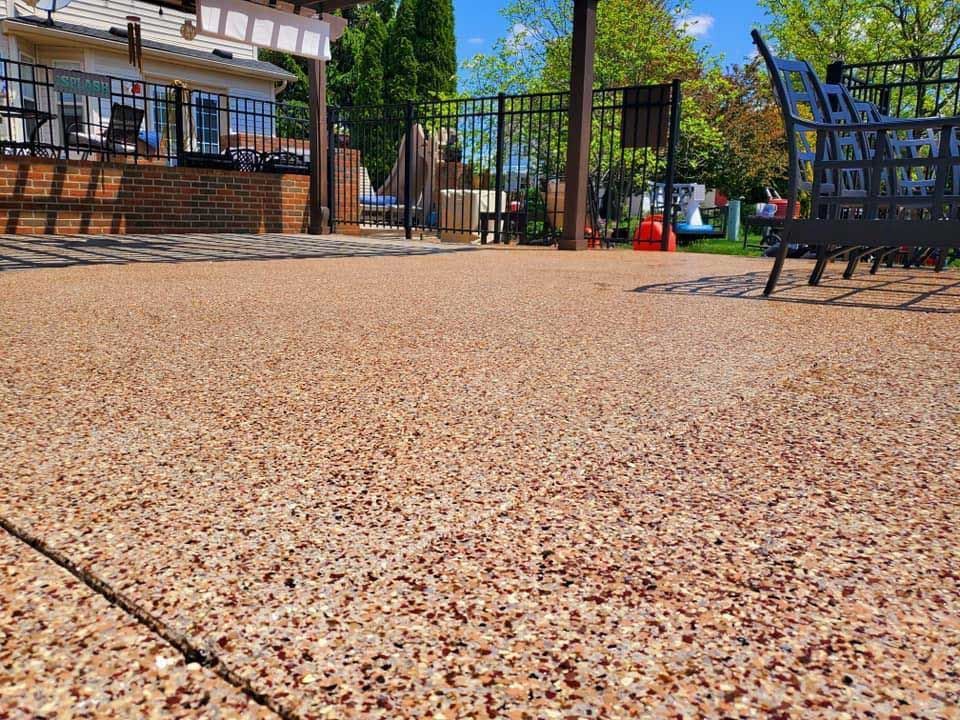 A patio with a bench and a fence in the background.
