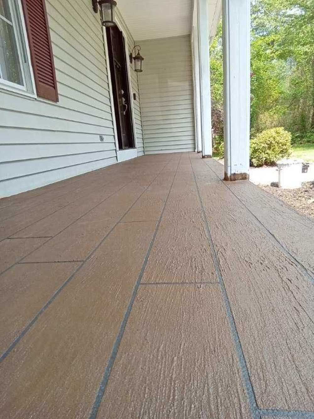 A porch with a wooden floor and a white house in the background.