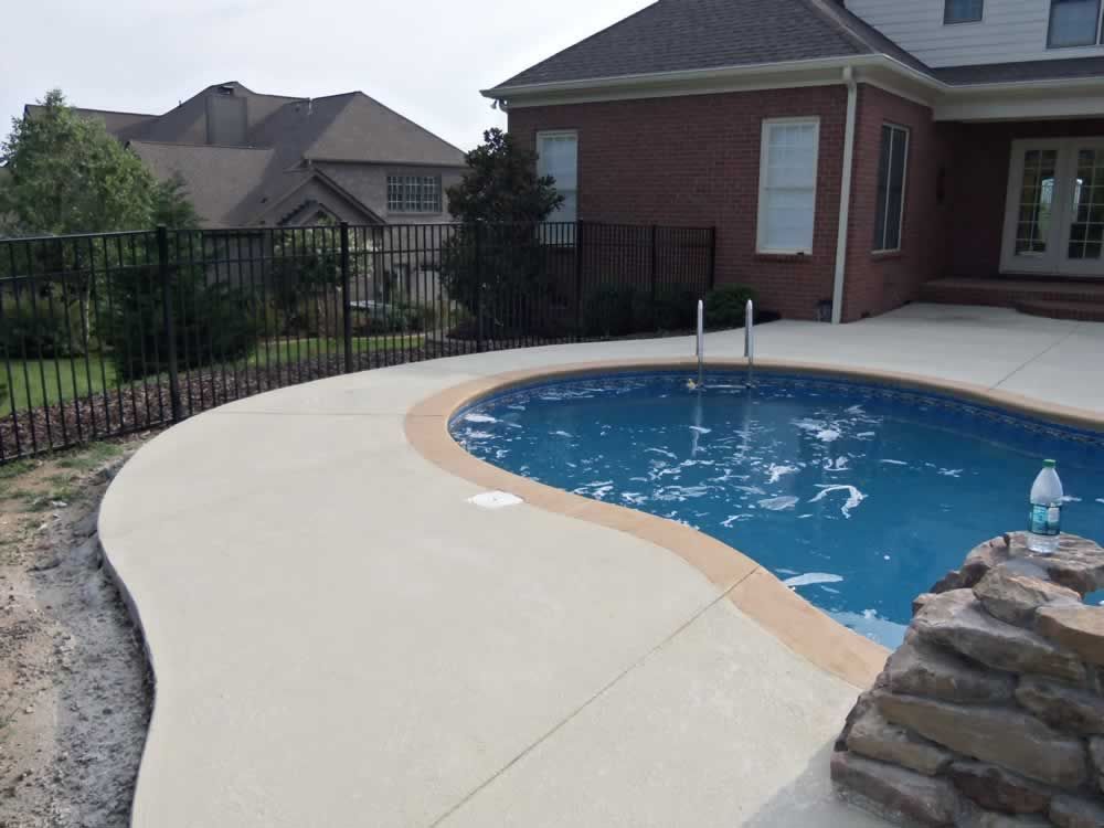 A large swimming pool in front of a brick house