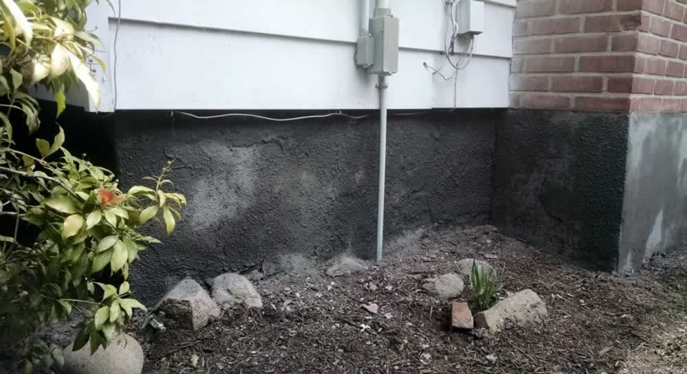 A house with a brick wall and a black foundation.
