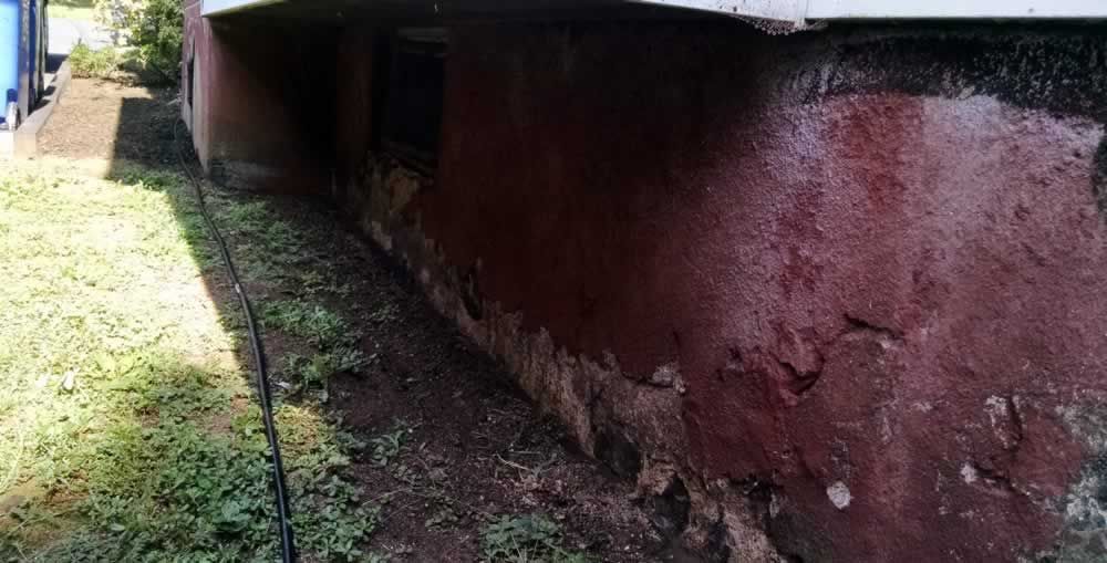A close up of a red wall next to a grassy field.