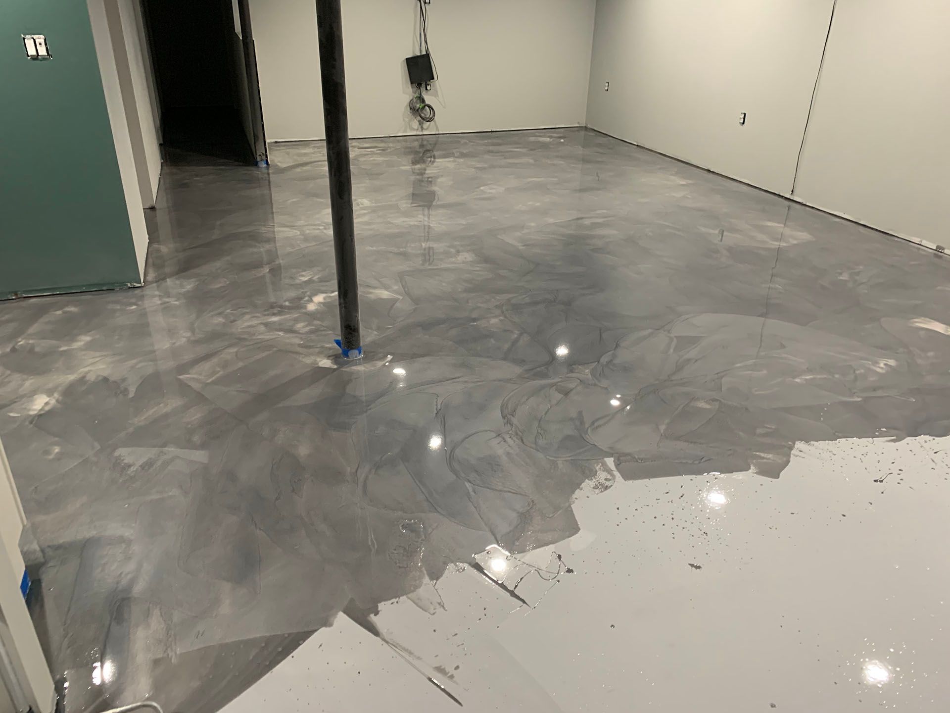 A basement with a metallic floor being painted.