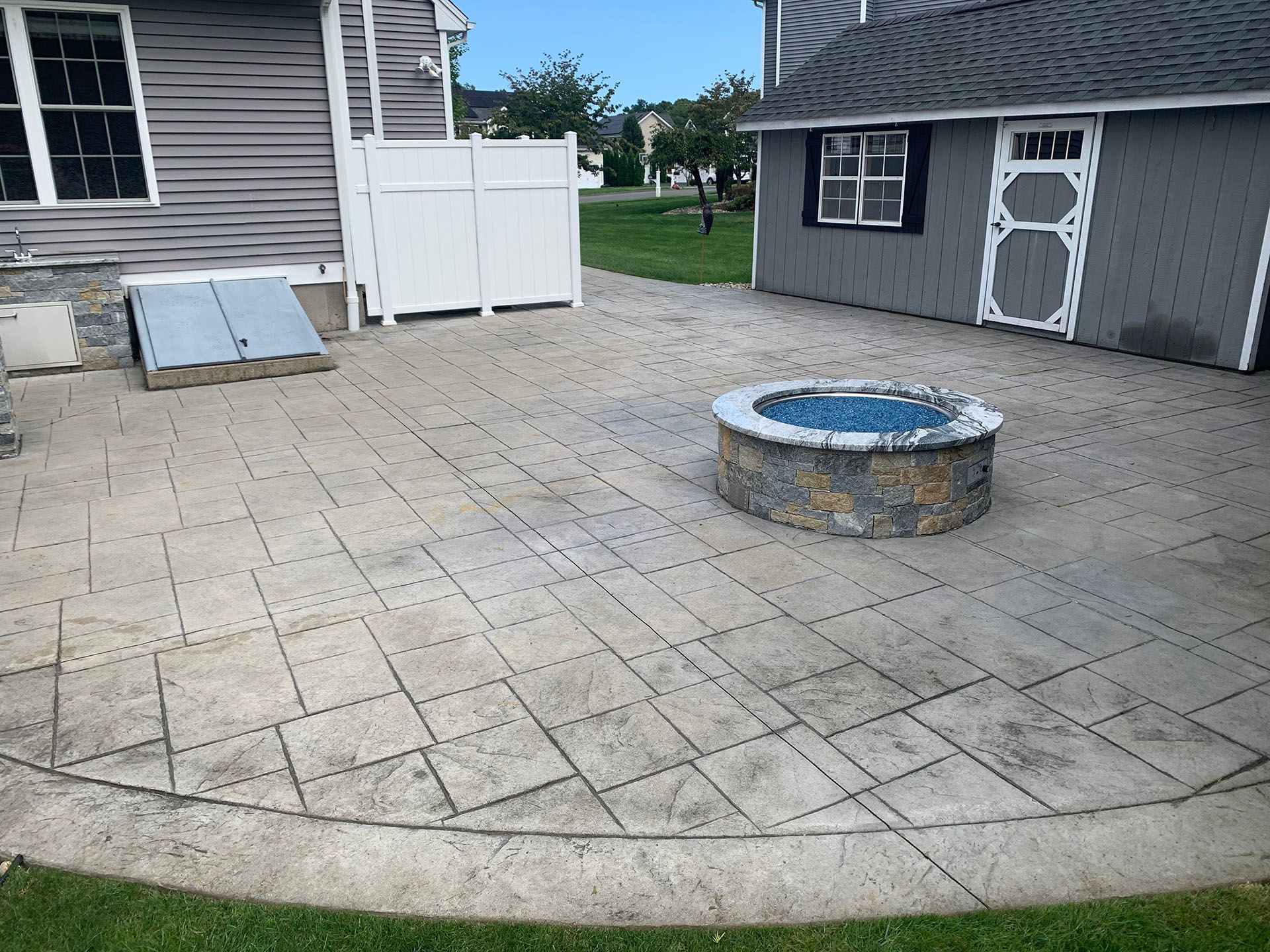 A fire pit is sitting on a patio in front of a house.