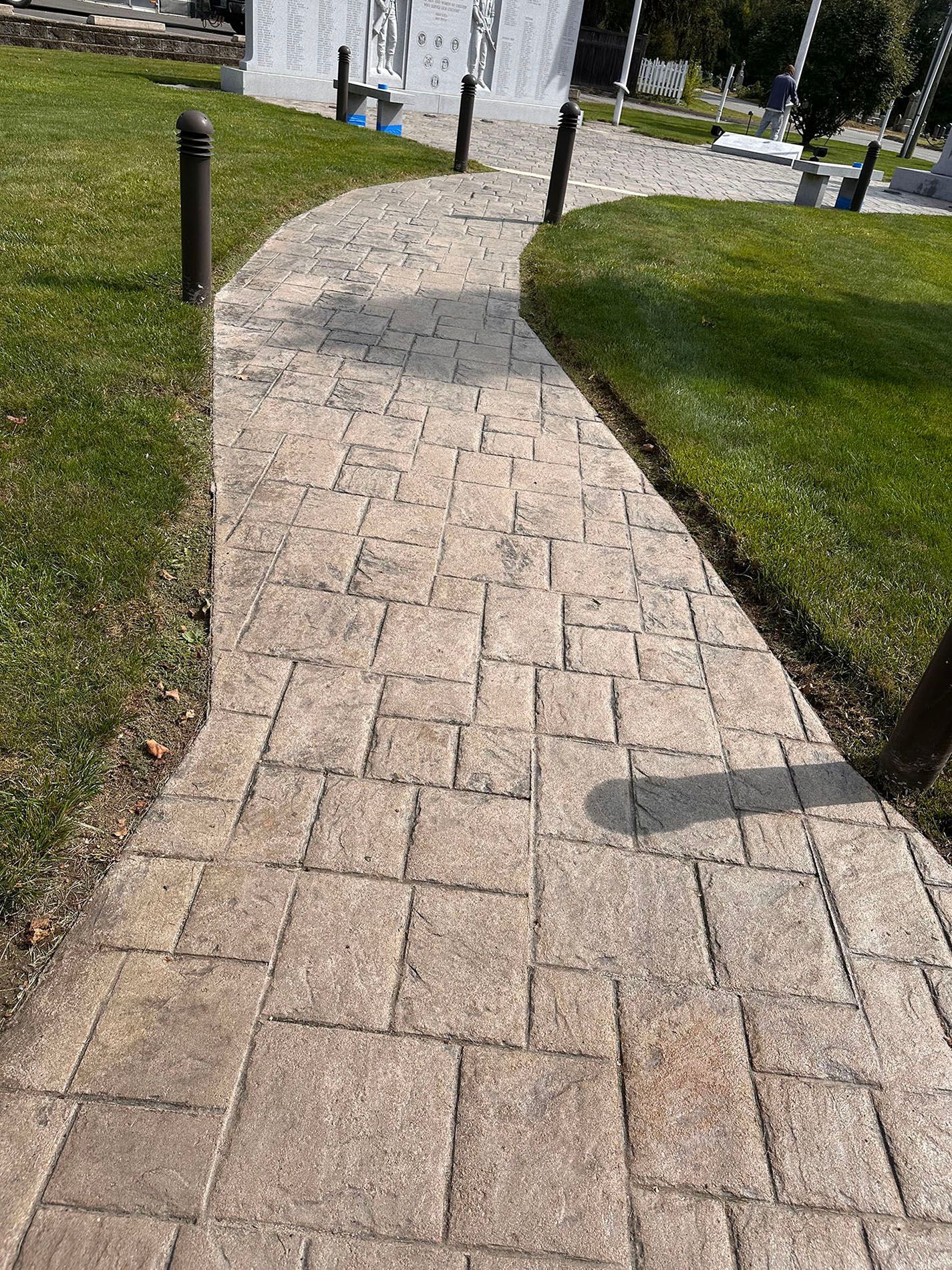 A brick walkway leading to a grassy field.