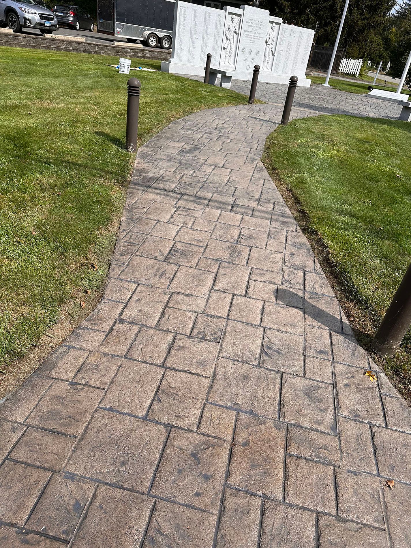 A brick walkway going through a grassy field.