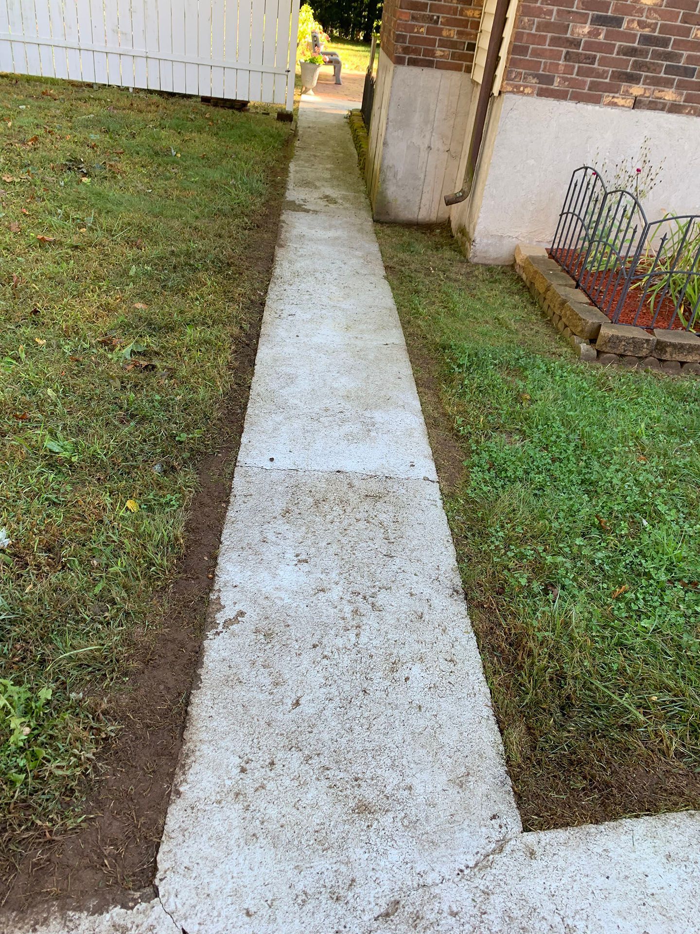 A concrete walkway leading to a brick house.