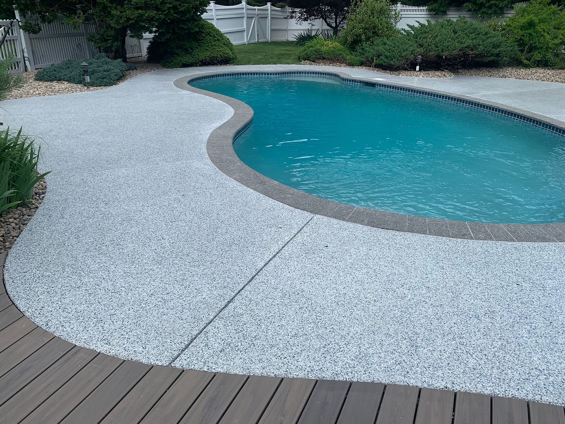 A large swimming pool with a wooden deck surrounding it.