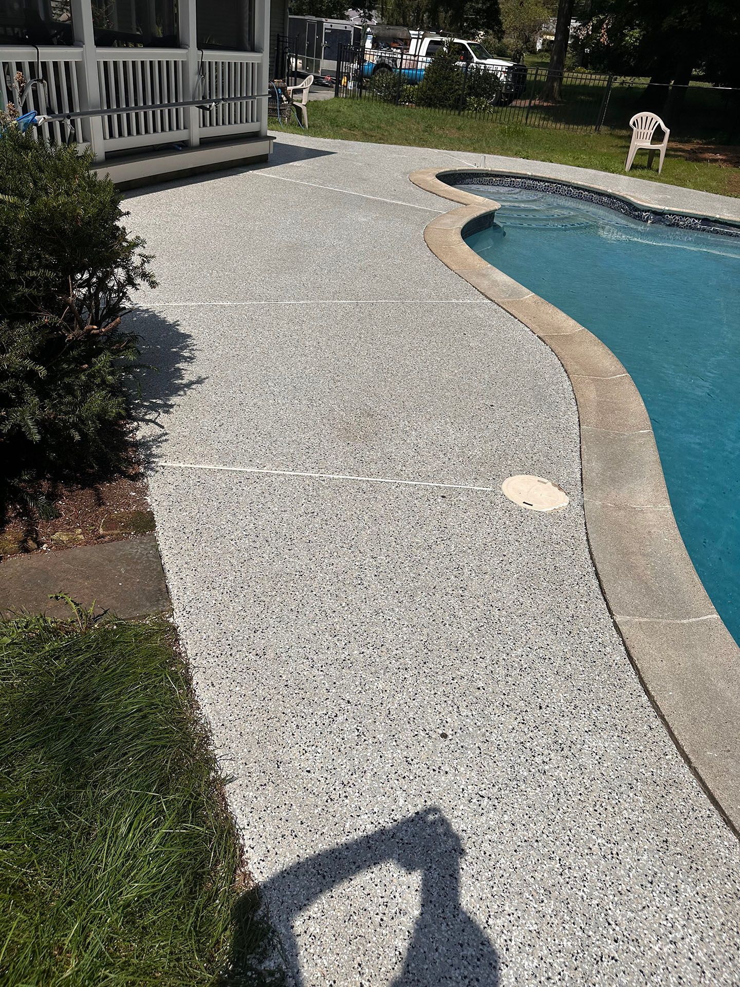 A concrete walkway leading to a swimming pool in a backyard.