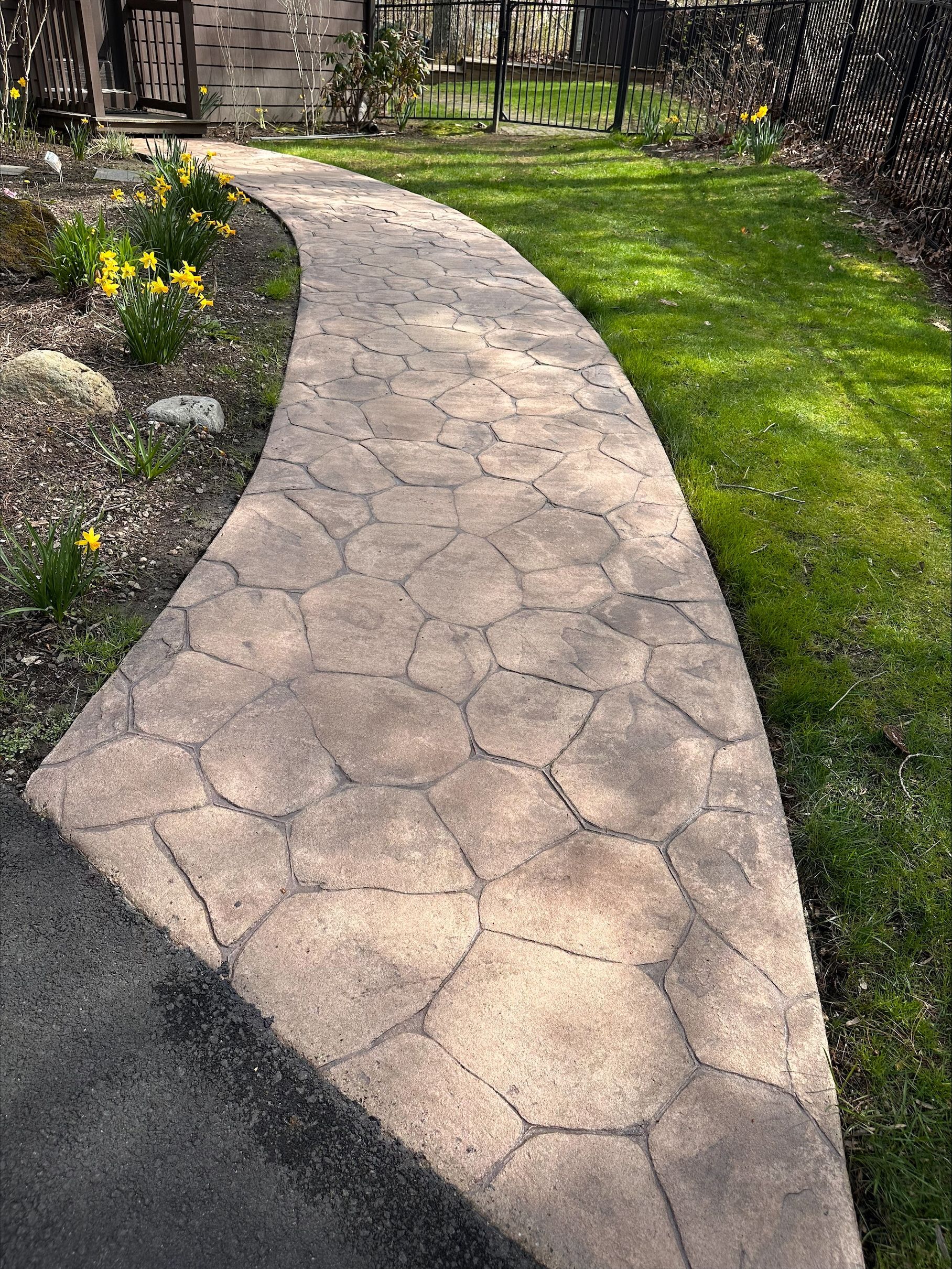 A stone walkway going through a lush green yard.