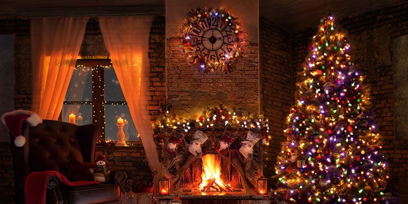 Cozy living room with glowing fireplace, lit Christmas tree, candles, and warm holiday decor