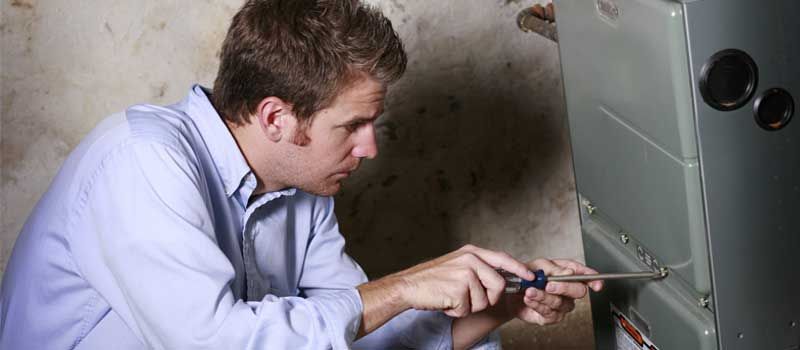 Technician using a screwdriver to repair a wall-mounted metal appliance