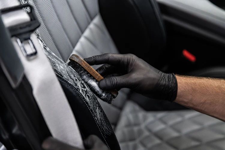 A person is cleaning a car seat with a brush.