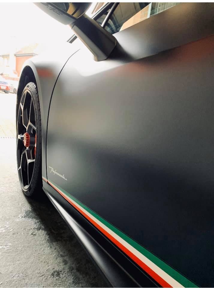 A black car with a red green and white stripe on the side