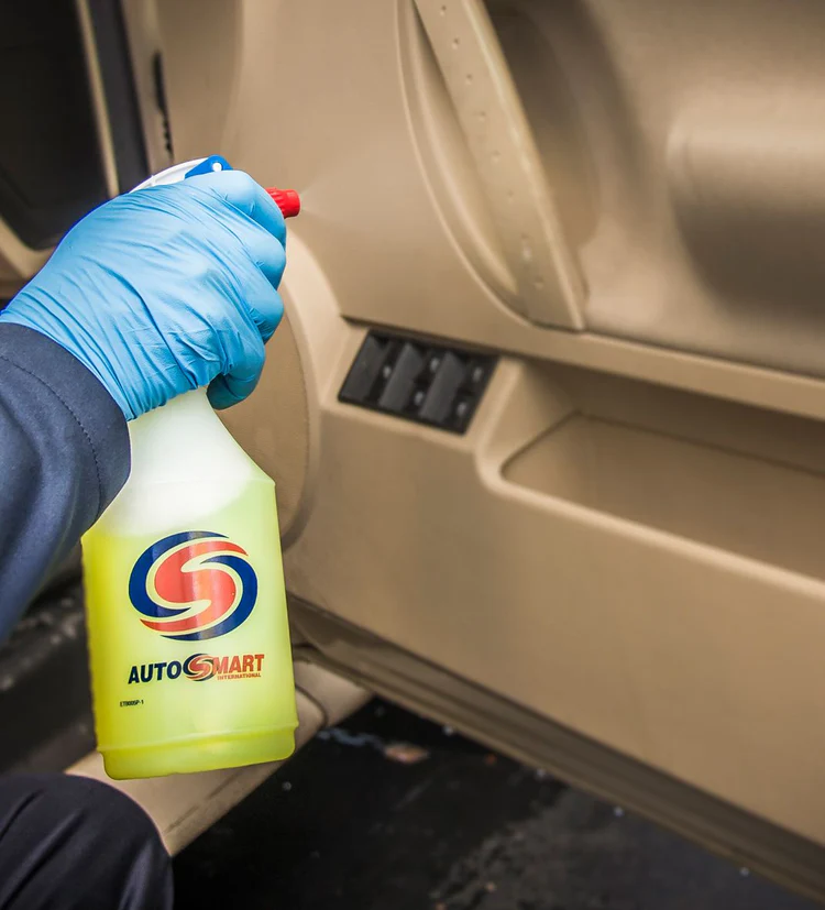 A person is holding a bottle of autosmart cleaner