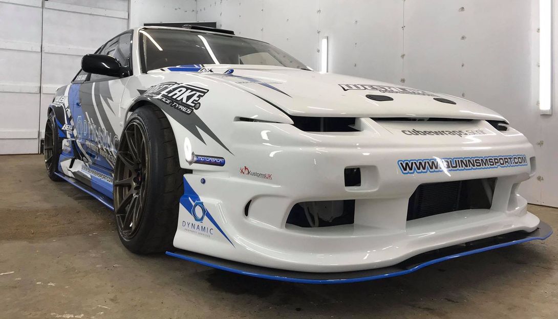 A white and blue sports car is parked in a garage.