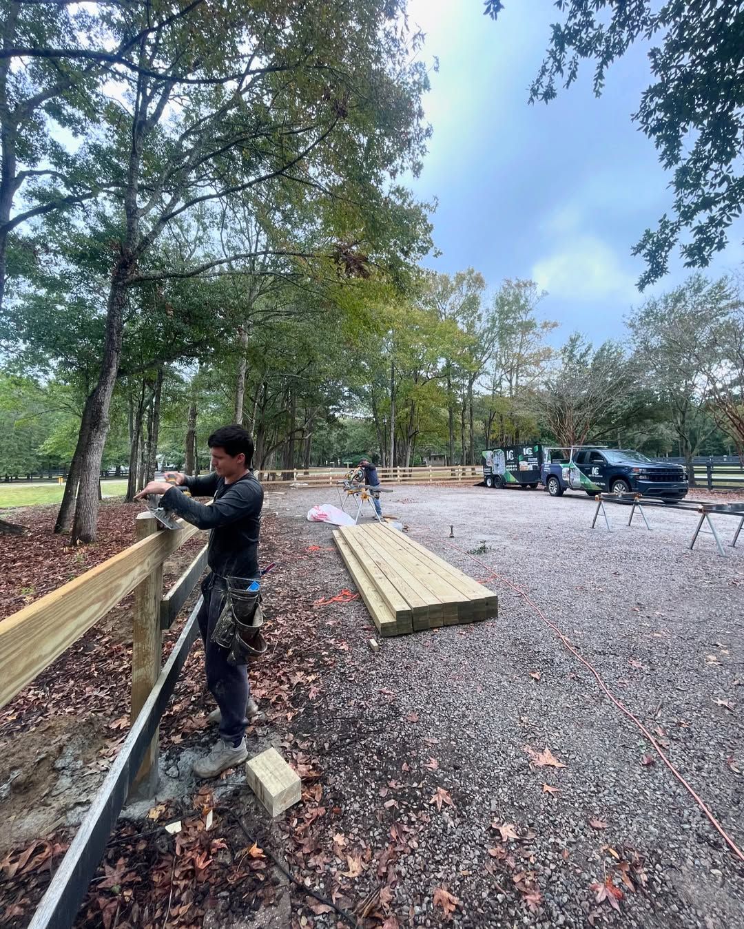A man is working on a wooden fence in a park.
