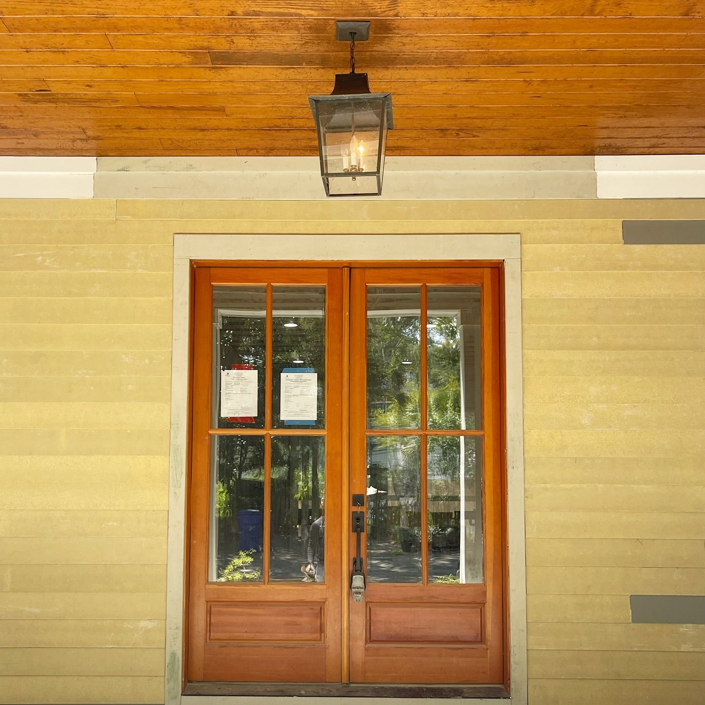 A wooden door with a lantern hanging from the ceiling above it.