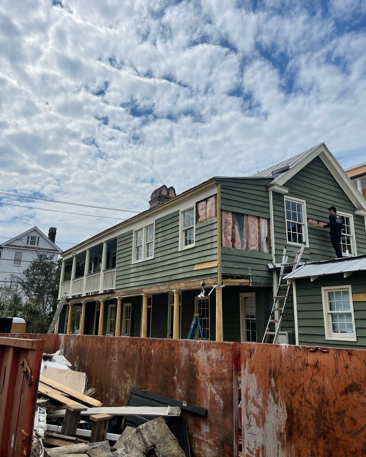A man is standing on the roof of a house under construction
