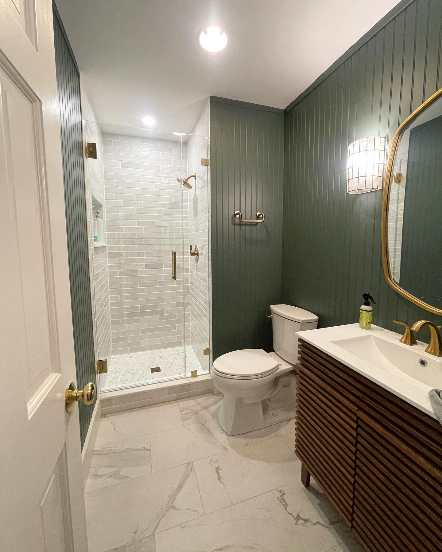 A bathroom with a toilet , sink , shower and mirror.